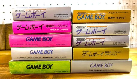 時代ごとに仕様の異なるゲームボーイソフトの箱を横から積み重ねて並べた写真。箱サイズや表記、構造の違いから、発売時期による変化が確認できる構成です。