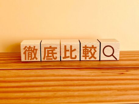 木製ブロックに「徹底比較」と書かれた文字と虫眼鏡アイコン。ゲーム出張買取おすすめ店のサービス比較をイメージした写真