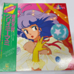『魔法の天使クリィミーマミ』のドラマ編LPレコード。マミのイラストが描かれたカラフルなジャケットに、緑色の帯が付属している。