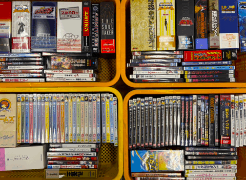 アニメや特撮関連のDVDボックスや単品ソフトが複数詰められた黄色いカゴ。90年代〜2000年代作品を中心とした大量買取品。