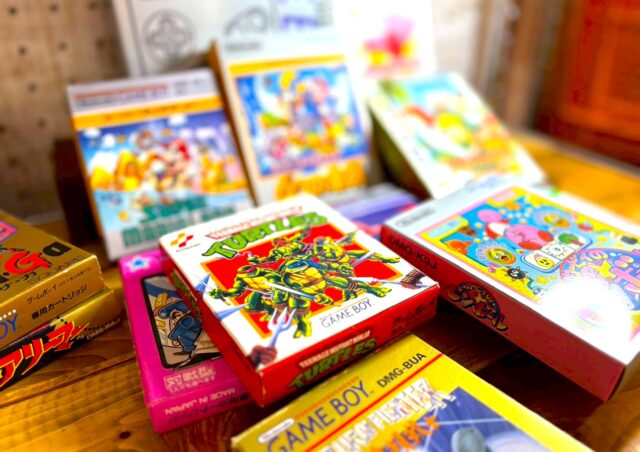 机の上に複数のゲームボーイソフトの箱付き個体が並べられている写真。初回版・限定版を含むタイトルが混在し、パッケージ仕様や存在感の違いから市場での評価差が生まれることを示すアイキャッチ画像です。